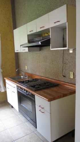 a kitchen with white cabinets and a stove top oven at Hotel Villa Monarca Inn in Zitácuaro