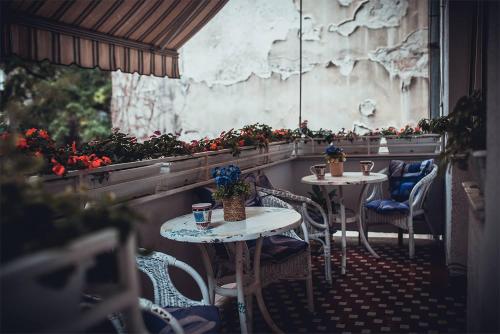 two tables and chairs in a restaurant with flowers at Hostel Beogradjanka in Belgrade