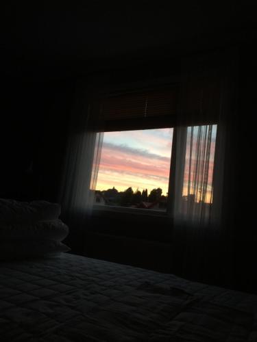 a bedroom with a bed and a window with a sunset at Mittes Rum in Alingsås