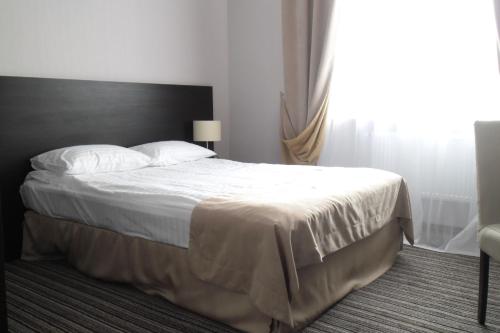 a bedroom with a bed with white sheets and a window at Optima Sumy in Sumy