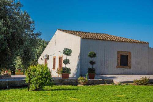 a white building with potted trees in a yard at B&B Le Balate in Augusta