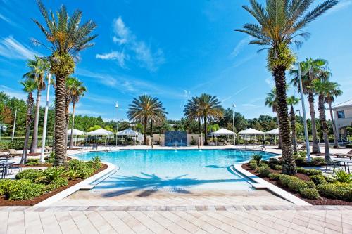 a swimming pool with palm trees and umbrellas at Monumental Hotel Orlando in Orlando