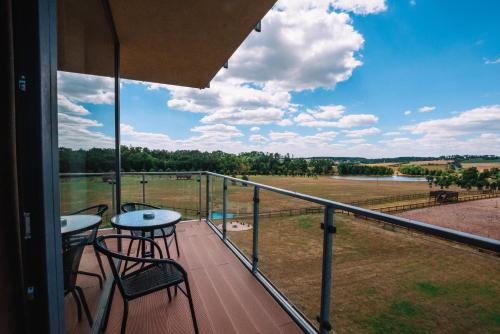 a balcony with two tables and a view of a field at K-Triumf Resort in Velichovky