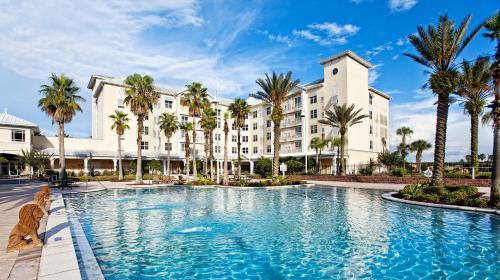 a large pool in front of a building with palm trees at Monumental Hotel Orlando in Orlando