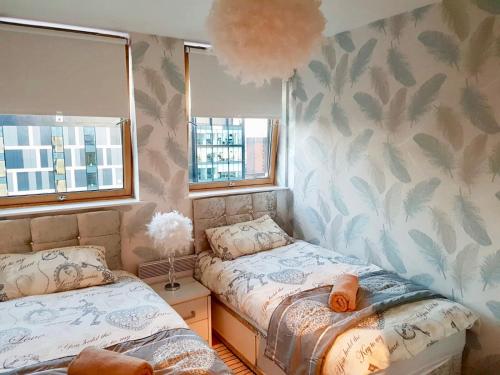 ein Schlafzimmer mit zwei Betten und zwei Fenstern in der Unterkunft Glasgow Central Station SKYLINE Apartment with Parking (2 bedrooms, 2 bathrooms, 1 living room-Kitchen) in Glasgow