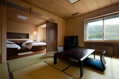 a bedroom with a bed and a table and a window at Shogetsu Grand Hotel in Jozankei