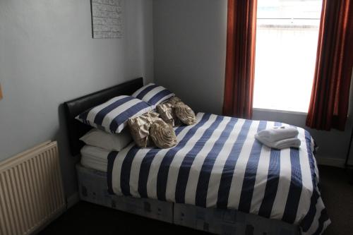a small bedroom with a bed with blue and white stripes at The Vale Apart Hotel in Hull