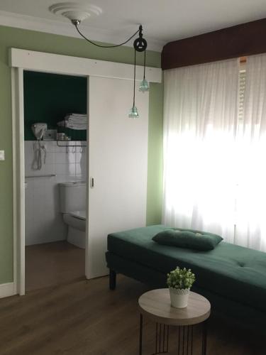 Un dormitorio con una cama verde y una mesa en Las Palomas, en Porto de Espasante