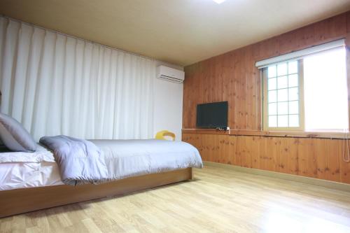 a bedroom with a bed and a flat screen tv at Daegwanryeong Rodem Tree Pension in Pyeongchang 