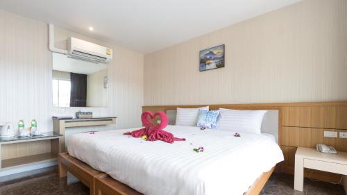 a bedroom with a large bed with a pink ribbon on it at Anda Beachside Hotel in Karon Beach