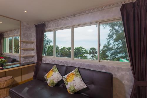a living room with a leather couch and windows at Anda Beachside Hotel in Karon Beach