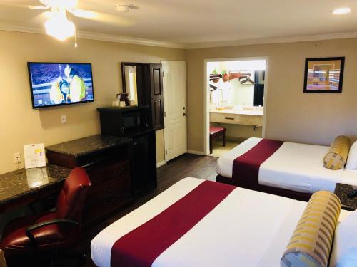 a hotel room with two beds and a television at Dynasty Suites Hotel in Riverside