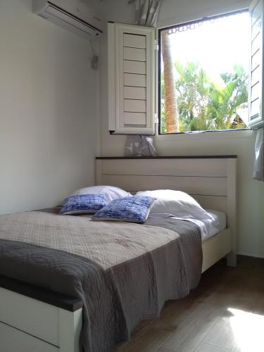 a bed with two pillows in a bedroom with a window at Sonella Bungalow in Le Gosier