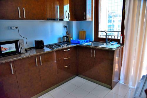 Una cocina con armarios de madera, fregadero y microondas. en Aden Apartments, en Tiflis