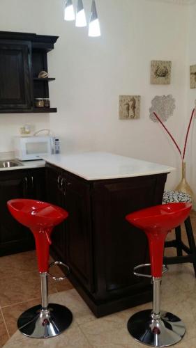 a kitchen with two red stools in front of a counter at Apartamento Frente Al Mar in San Felipe de Puerto Plata