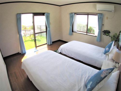 two beds in a room with two windows at Sea side house Ogimi in Ujimi