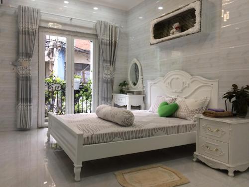 ein weißes Schlafzimmer mit einem weißen Bett und einem Fenster in der Unterkunft The Moana House in Ho-Chi-Minh-Stadt