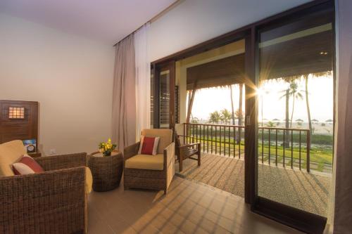 a living room with chairs and a balcony with a view at Eskala Hotels and Resorts in Ngwesaung
