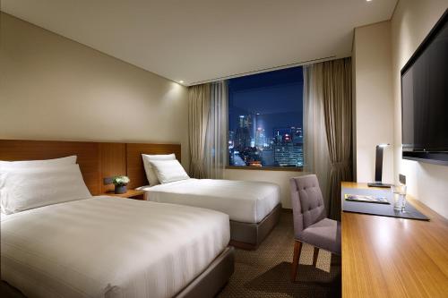 LOTTE City Hotel Myeongdong في سول: غرفة فندقية بسريرين ونافذة