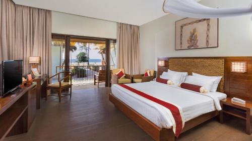 a hotel room with a bed and a television at Eskala Hotels and Resorts in Ngwesaung