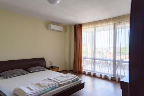 a bedroom with a bed and a large window at Gradina in Chernomorets