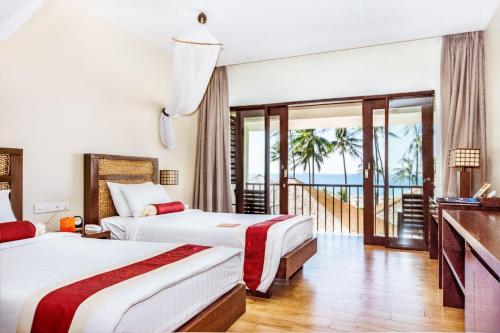 a hotel room with two beds and a balcony at Eskala Hotels and Resorts in Ngwesaung