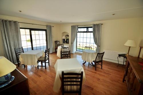 un soggiorno con tavoli, sedie e finestre di Barrow Lodge a Tralee
