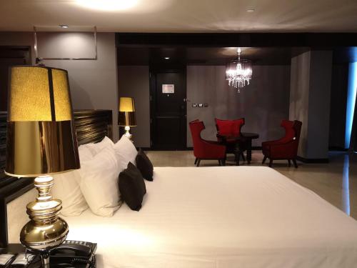a bedroom with a bed with a lamp and chairs at TSix5 Quarter in Pattaya North