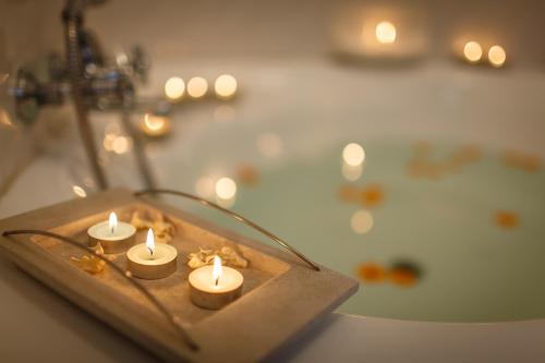 a group of candles on a wooden tray in front of a tub at Okiep Country Hotel in OʼOkiep