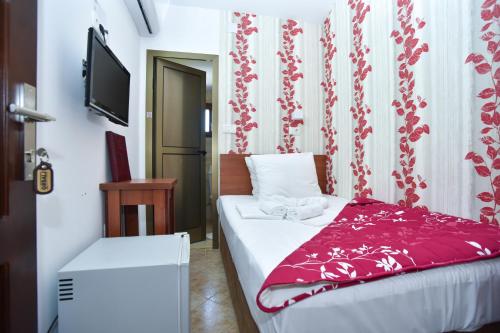 a bedroom with a bed with a red blanket at Hotel Grbalj in Budva