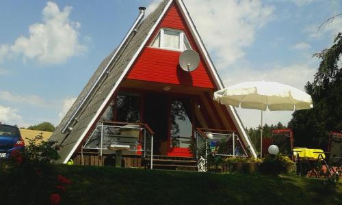 a house with a red roof and a white umbrella at Eifeler Finnhaus mit Sauna in Dockweiler