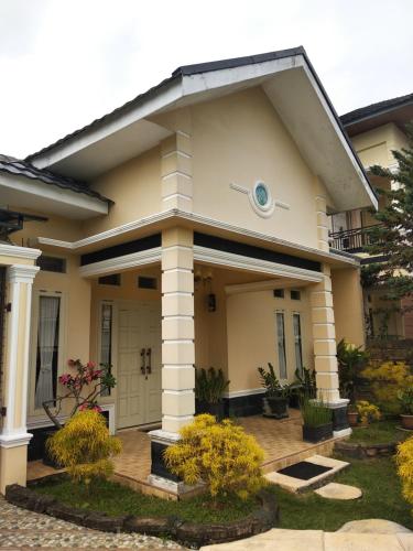 a small yellow house with a porch at Narahma Homestay in Bukittinggi