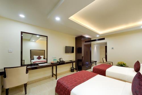 a hotel room with two beds and a desk and a mirror at Hotel Lance International in Nāgercoil