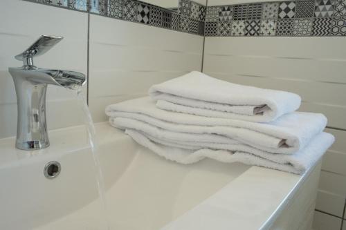 uma pilha de toalhas brancas sentadas num lavatório da casa de banho em Appart Hotel de la Souleuvre em Le Bény-Bocage