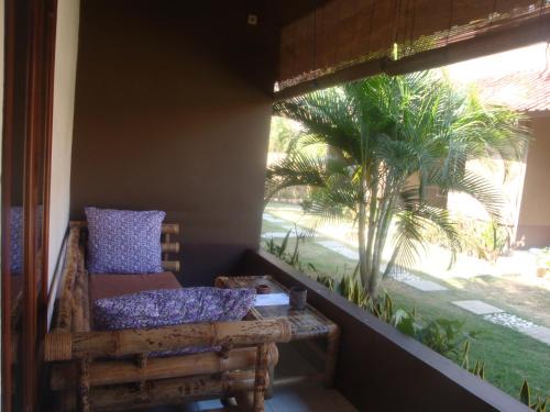 a porch with a chair and a palm tree at Relaxing Homestay in Kuta Lombok