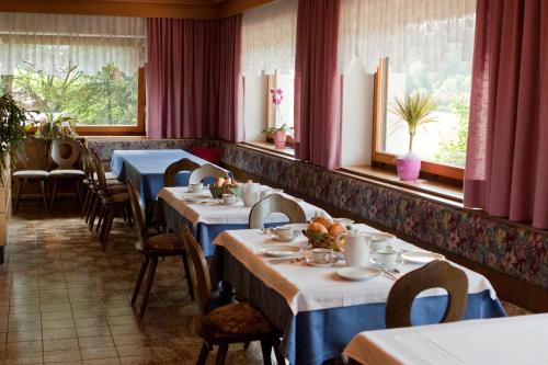 a dining room with tables and chairs and windows at Appartments Helvetia in Villabassa