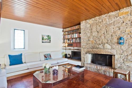 a living room with a couch and a stone fireplace at BmyGuest - Sesimbra Country Villa in Sesimbra