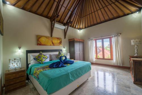 a bedroom with a large bed with a blue comforter at Mudha Bali Villa Sanur 4 Bedrooms in Sanur