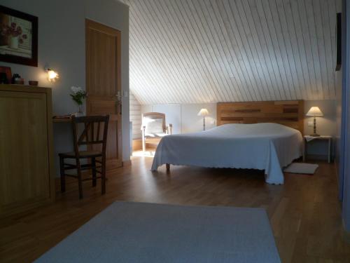 una camera con letto bianco e tavolo e sedie di La Clé des Chants a Tauxigny