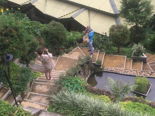 two people taking pictures of a pond in a garden at Train View Chalet in Bandarawela