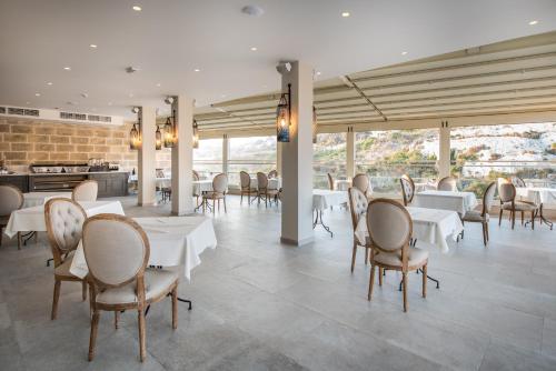a dining room with white tables and chairs at Cesca's Boutique Hotel in Xlendi