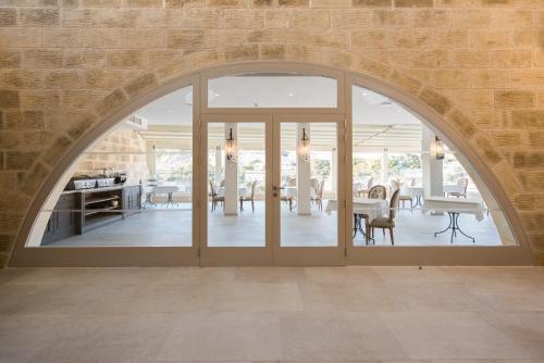 an arched glass door in a dining room with a table at Cesca's Boutique Hotel in Xlendi