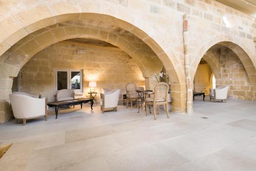 a room with a stone wall and a table and chairs at Cesca's Boutique Hotel in Xlendi