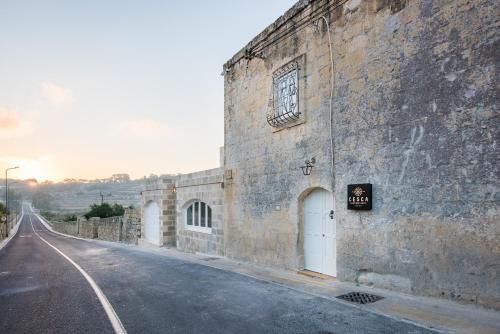 a large stone building with a door on the side of a road at Cesca's Boutique Hotel in Xlendi