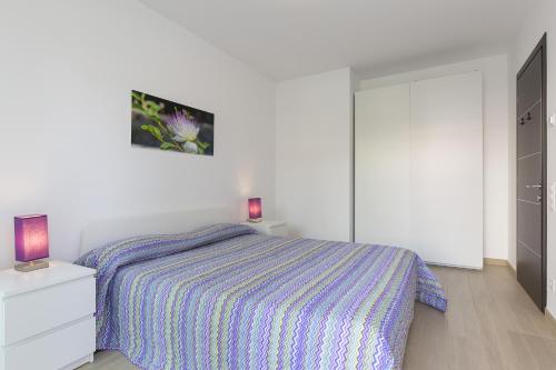 a white bedroom with a bed and a dresser at Roggia Apartments by Quokka 360 - central flats with parking space in Lugano