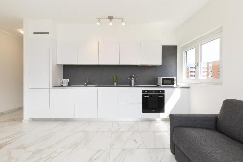 a kitchen with white cabinets and a couch at Roggia Apartments by Quokka 360 - central flats with parking space in Lugano
