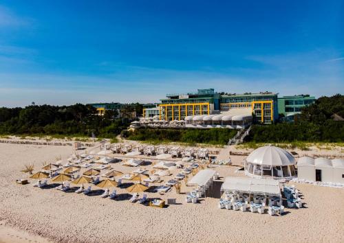 a group of umbrellas and chairs on a beach at Hotel Bryza Resort & Spa in Jurata