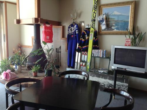 a dining room with a table and skis and a tv at Happokan in Hakuba