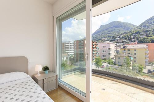 a bedroom with a bed and a large window at Roggia Apartments by Quokka 360 - central flats with parking space in Lugano