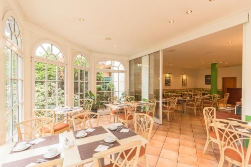 un restaurante con mesas, sillas y ventanas en Hotel Markgraf Leipzig, en Leipzig